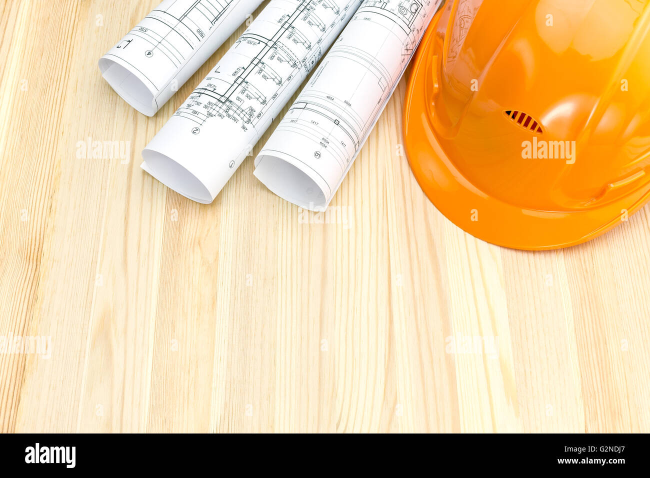 rolls of blueprints with orange safety helmet on wooden background ...