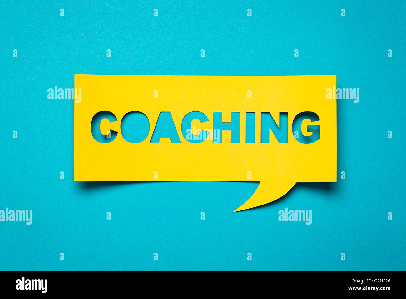 Bubble speech with cut out phrase 'coaching' in the paper. Stock Photo