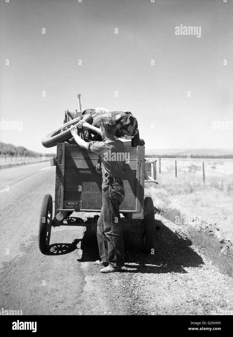 Drought Refugee from South Dakota on Highway Making Sure Nothing Falls off Trailer,Montana,USA,Arthur Rothstein for Farm Security Administration (FSA),July 1936 Stock Photo