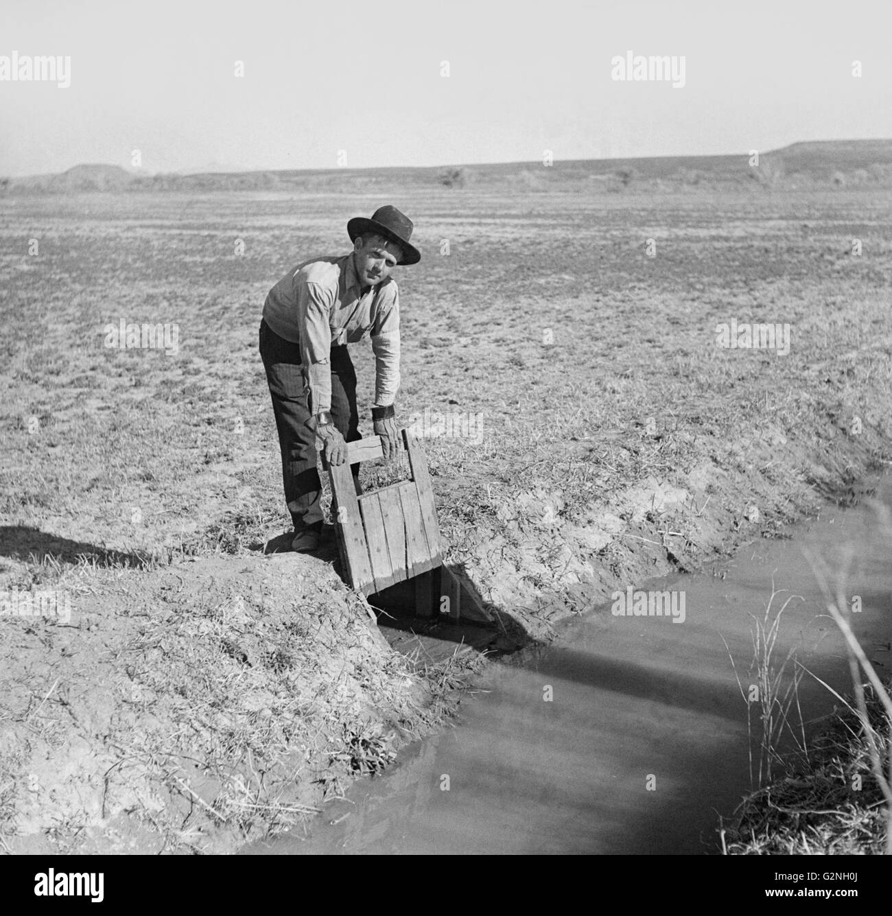 Farmer Opening Gate that Allows Water to Flow into Field from Irrigation Ditch, New Mexico, USA, Arthur Rothstein for Farm Security Administration (FSA), September 1936 Stock Photo