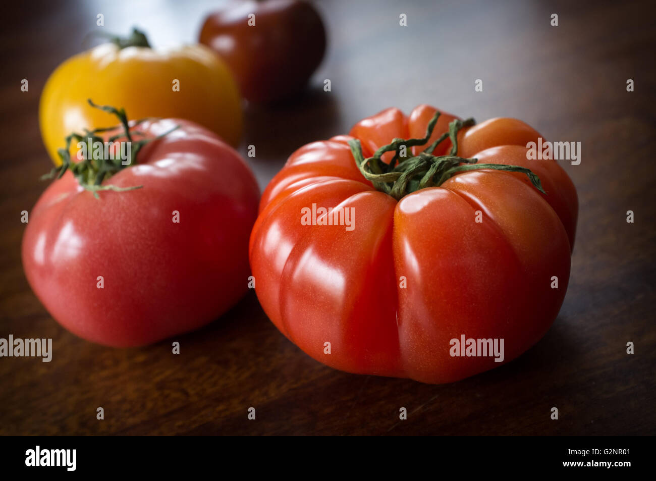 Colorful juicy heirloom or heritage tomatoes on wooden table Stock Photo