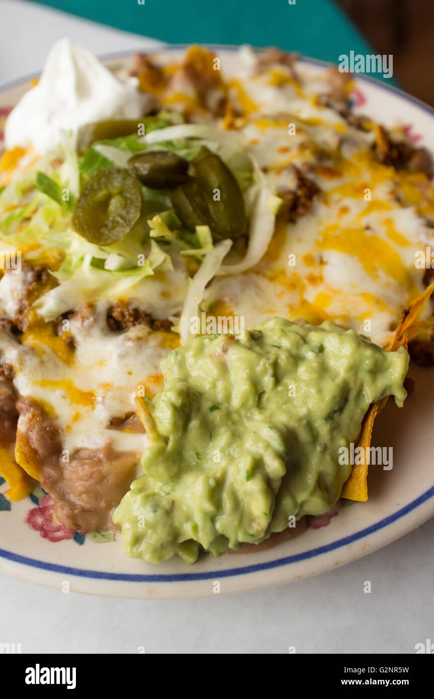 Mexican beef nachos with sour cream guacamole and melted shredded