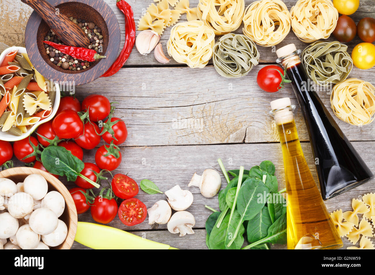 Fresh ingredients for cooking: pasta, tomato and spices over wooden table background with copy space Stock Photo