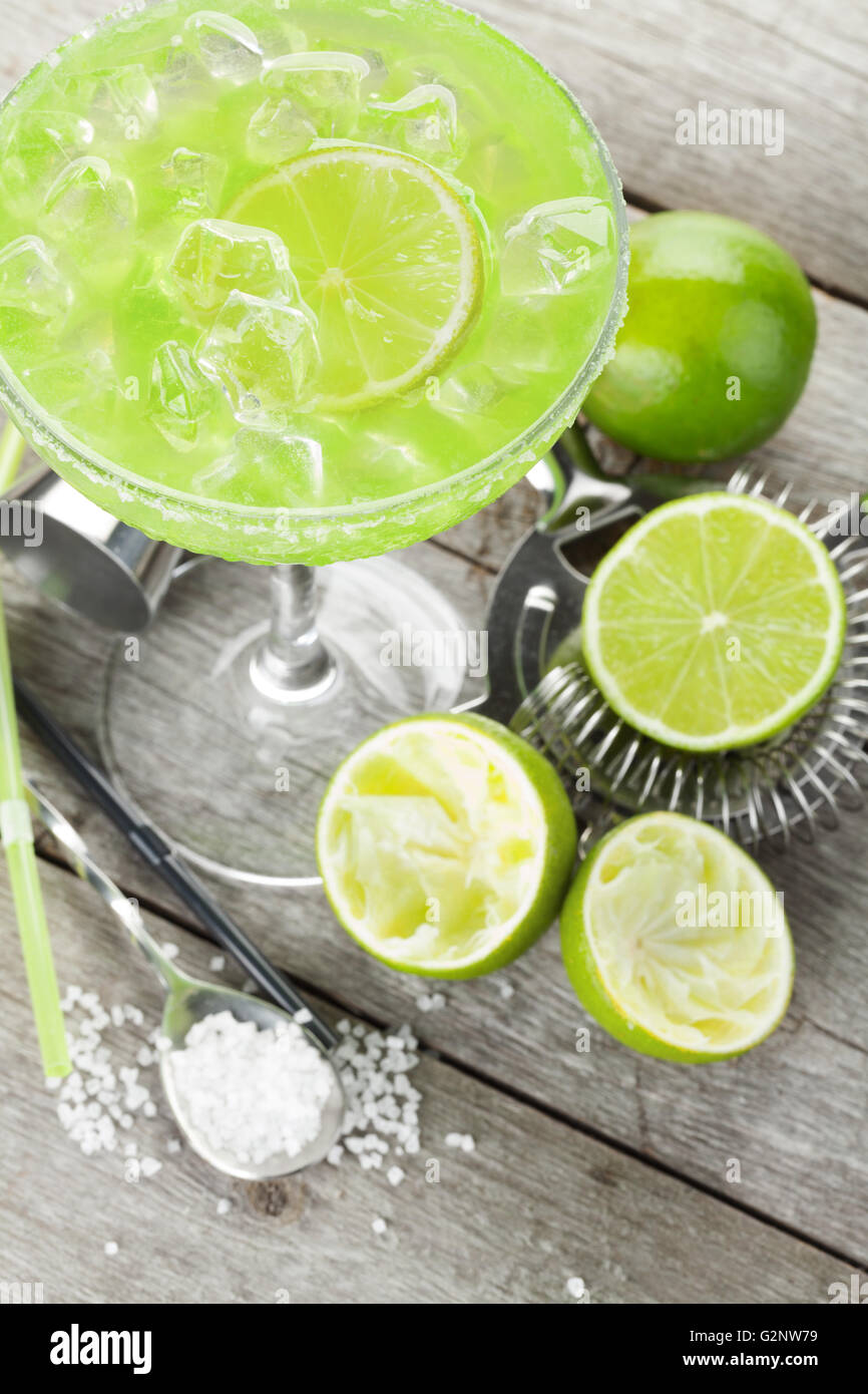 Classic margarita cocktail with salty rim on wooden table with limes ...