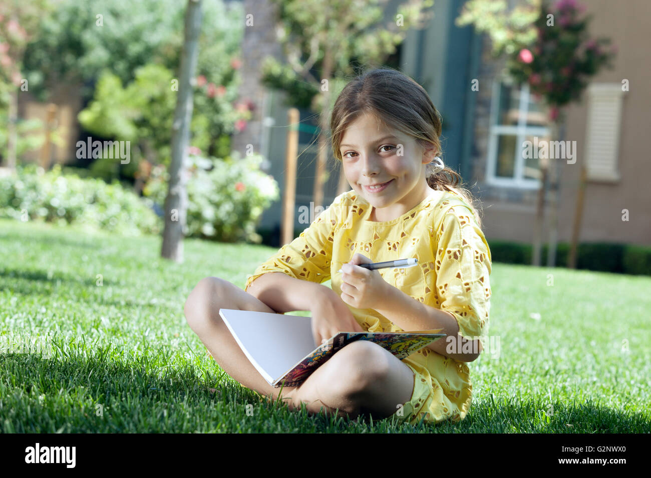 portrait of little girl studying on the grass in summer environment ...