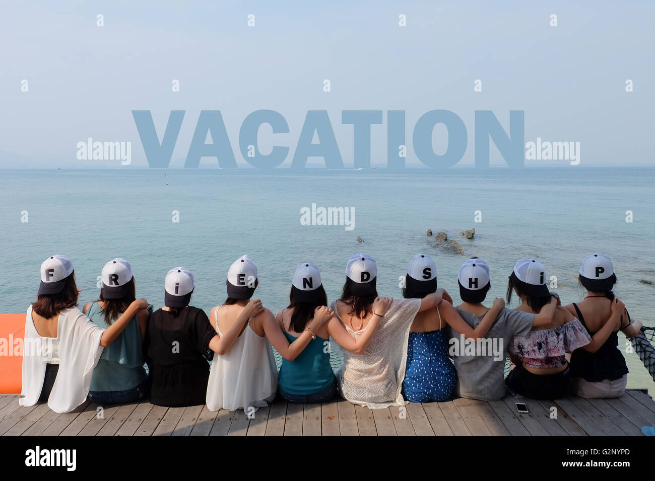 group of ten women friends sit hug together look VACATION blue sea sky. Stock Photo