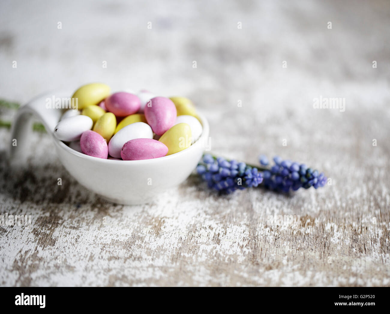 Bowl with bright pink, yellow and white sweet candy bonbons and Hyacinth Flowers Stock Photo