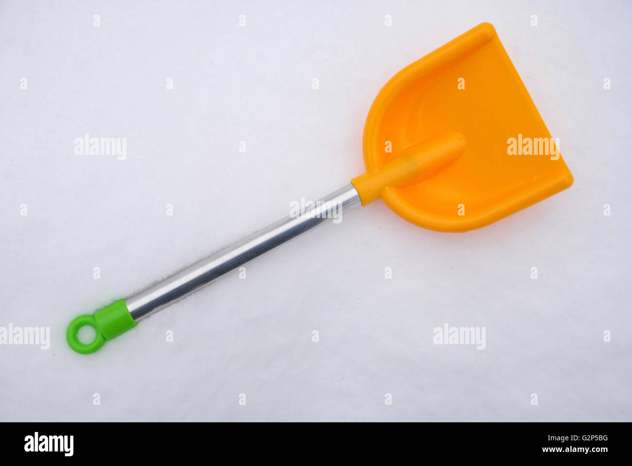 Childrens shovel into a snow. Children toy shovel with snow on background. Stock Photo