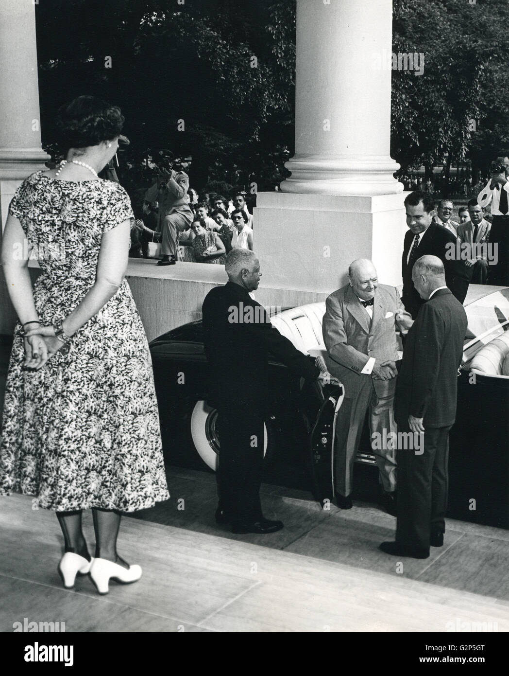 Mamie Eisenhower waits at the top of the steps as President Dwight Eisenhower greets Prime Minister Winston Churchill as he alights from a limousine at the White House. Vice-President Richard Nixon waits behind the British statesman. Stock Photo