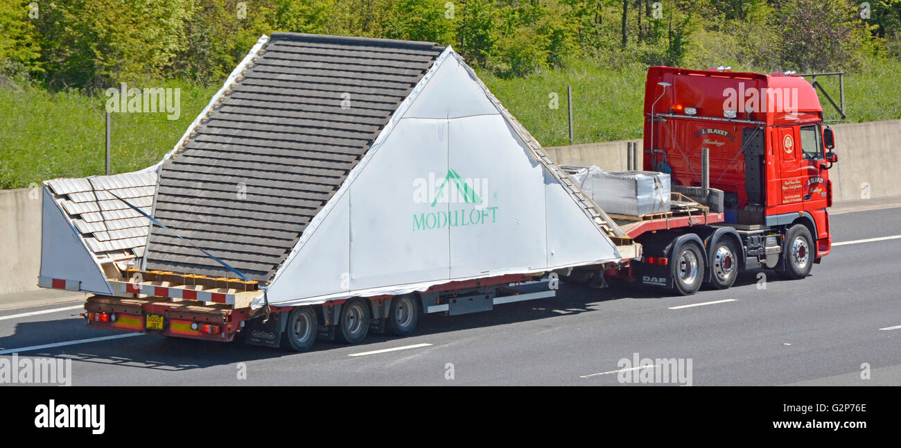 Transporting logistics lorry truck & oversize prefabricated factory built modular house loft conversion transported on low loader trailer UK motorway Stock Photo