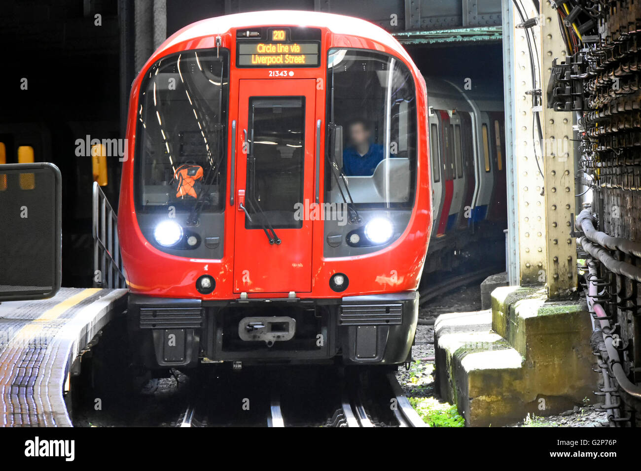 Front of Circle Line London Underground tube train and driver obscured face emerging from tunnel entering train station platform England UK Stock Photo