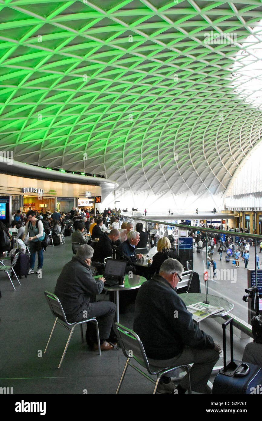 Kings Cross train station London tables & seating for cafe users on mezzanine floor inside departures concourse with green ceiling lights England UK Stock Photo