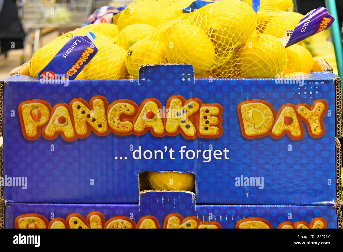 UK English supermarket food store shopping promotion display don't forget Pancake Day lemons sold in string bags supplied to shop in cardboard box Stock Photo