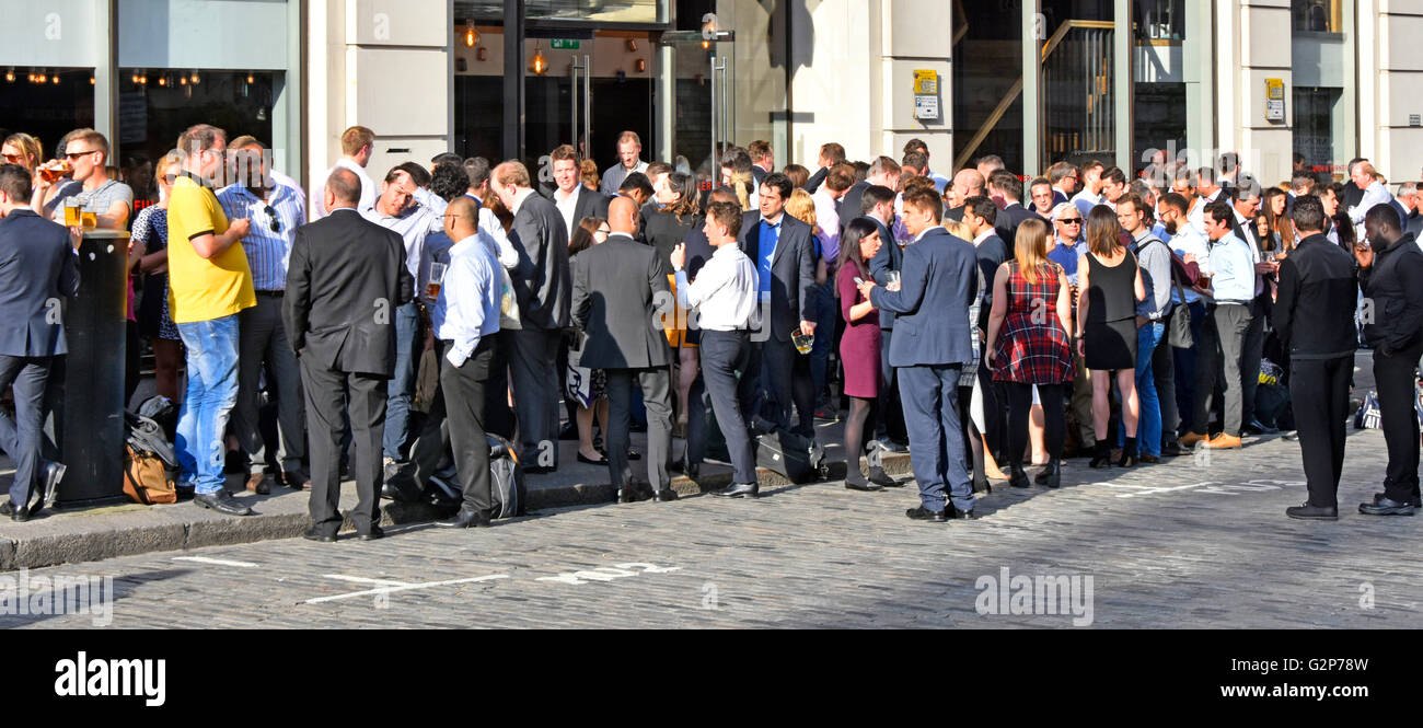 Predominately office workers standing talking chatting & drinking in the street outside bar restaurant premises in the City of London UK after work Stock Photo