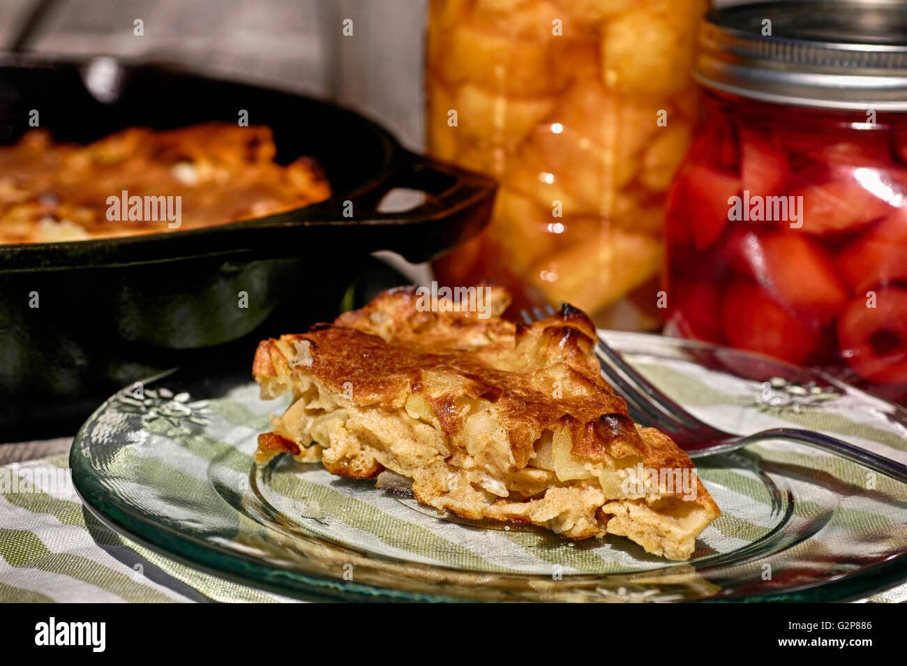 Apple pancake breakfast baked in cast iron skillet with mason jars of fruit Stock Photo
