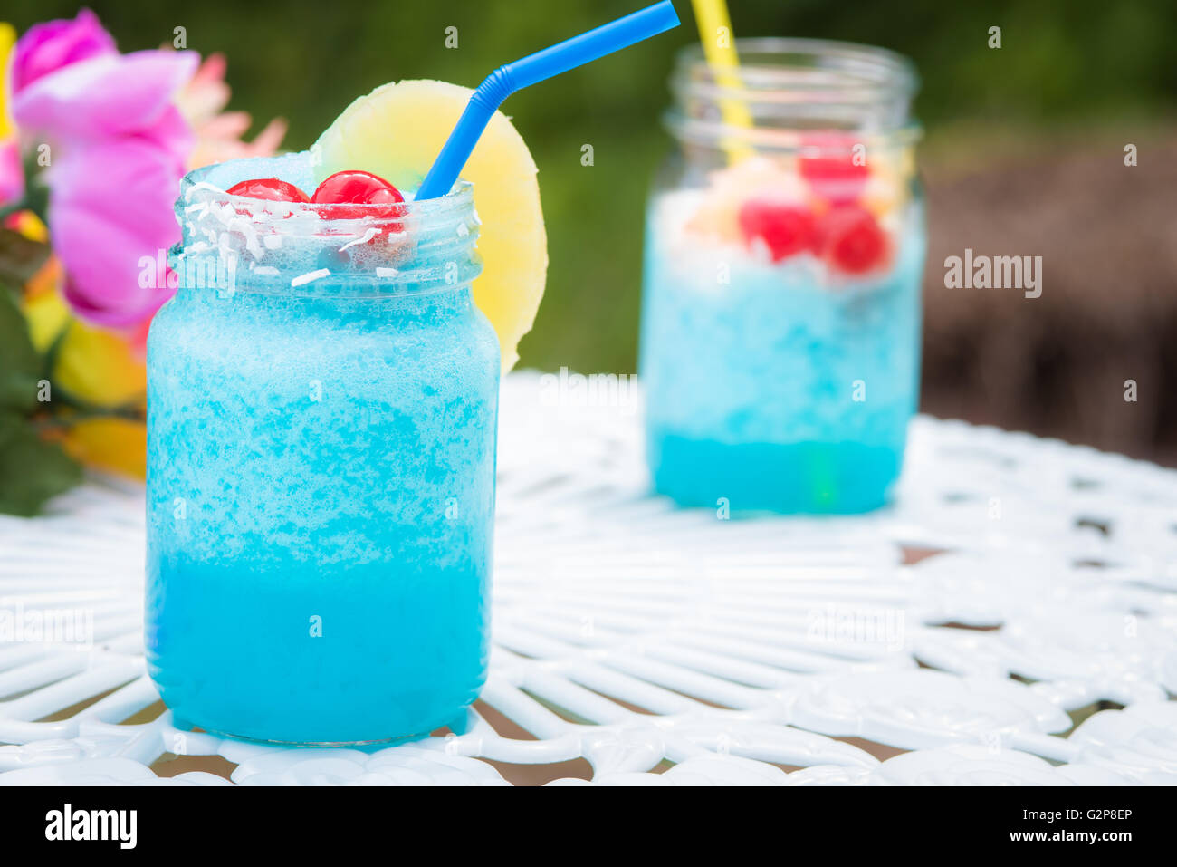 Blue cocktail drinks sitting on a white table in a mason jar Stock Photo