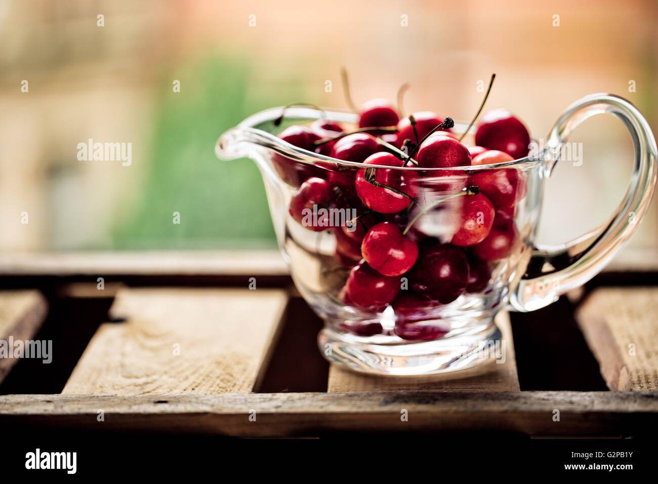 Cherries in Glass Bowl in front of Window Stock Photo