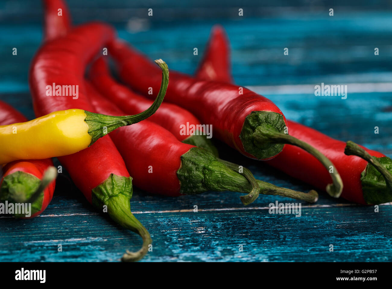 Red and Yellow Chili Pepper on blue wooden background Stock Photo