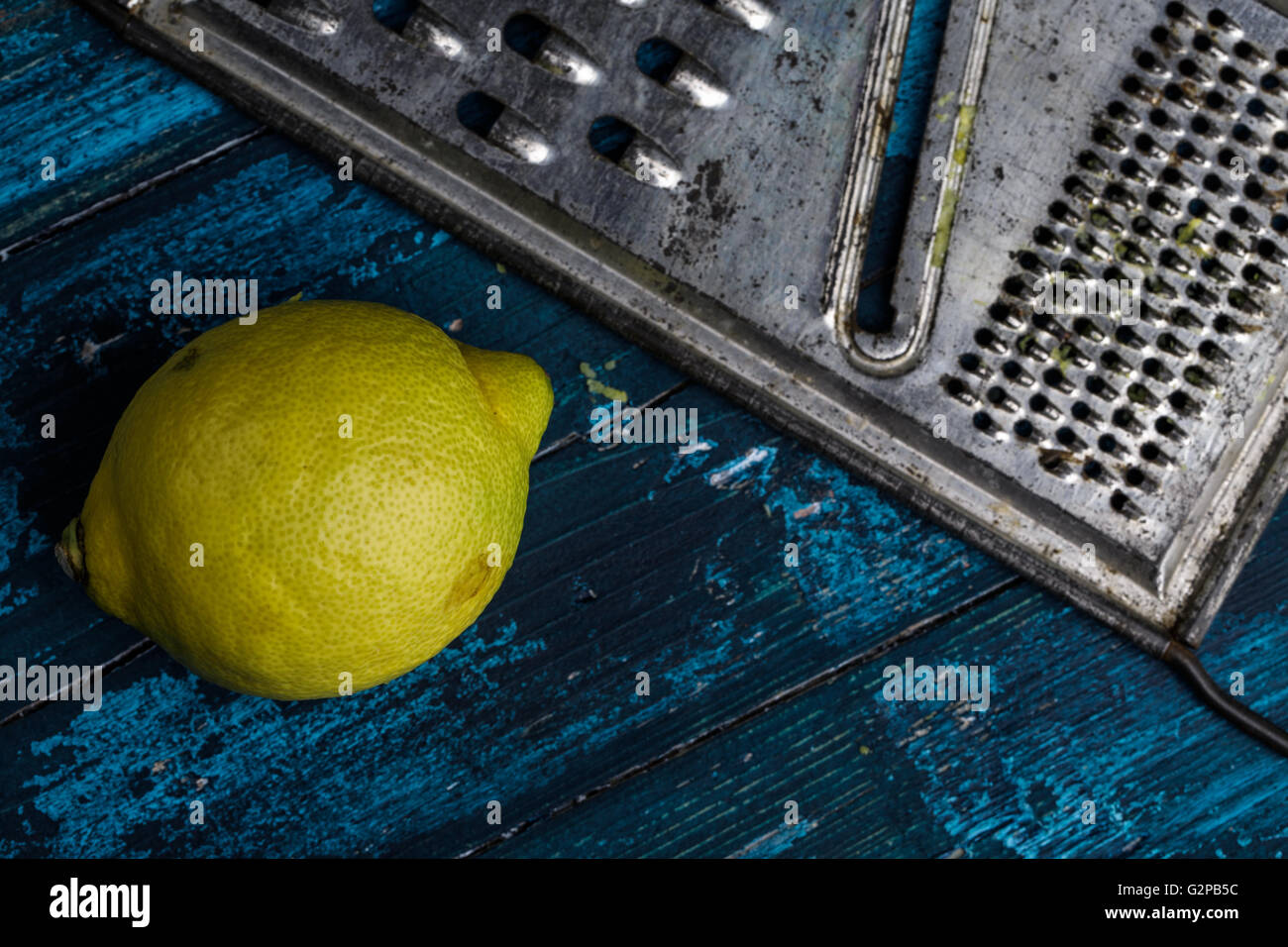 Fresh Lemon with metal grater on blue board Stock Photo