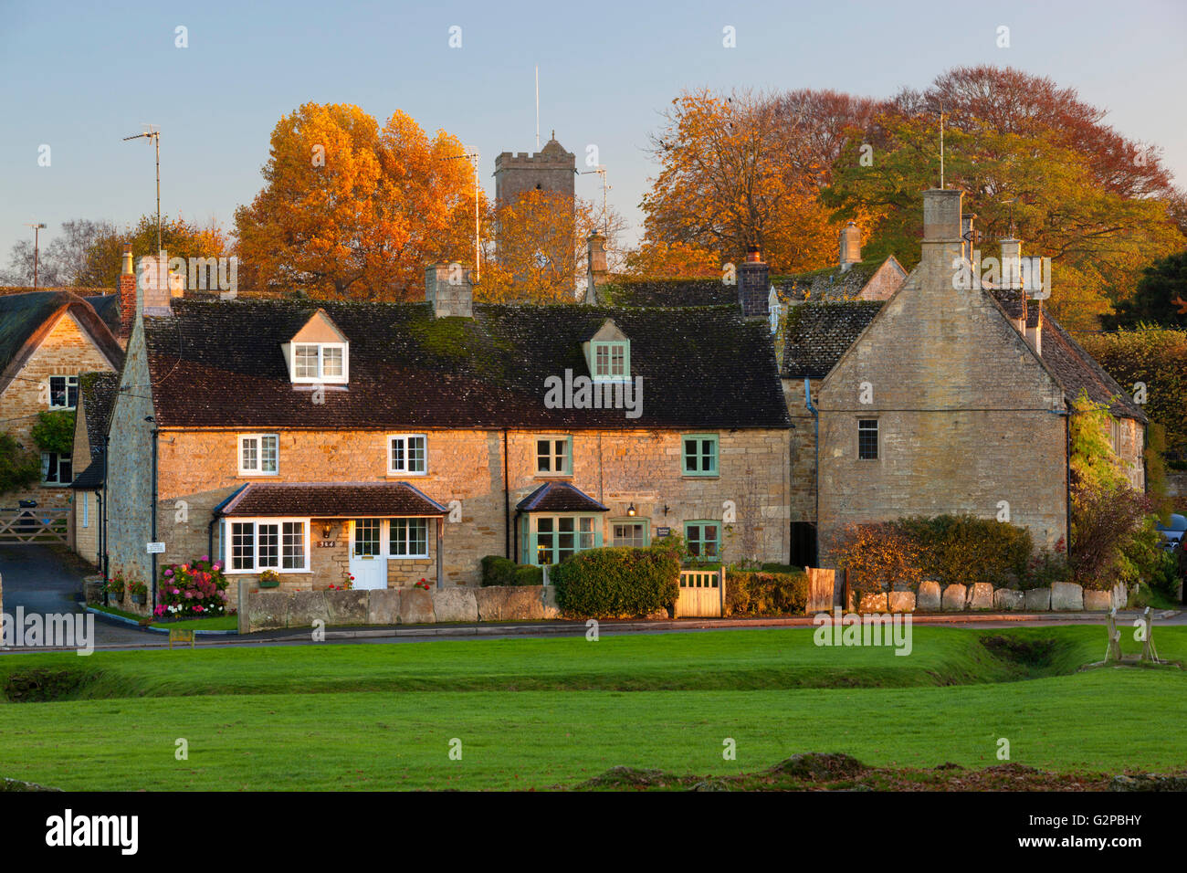 Cotswold stone cottages on village green in autumn, Bledington Stock