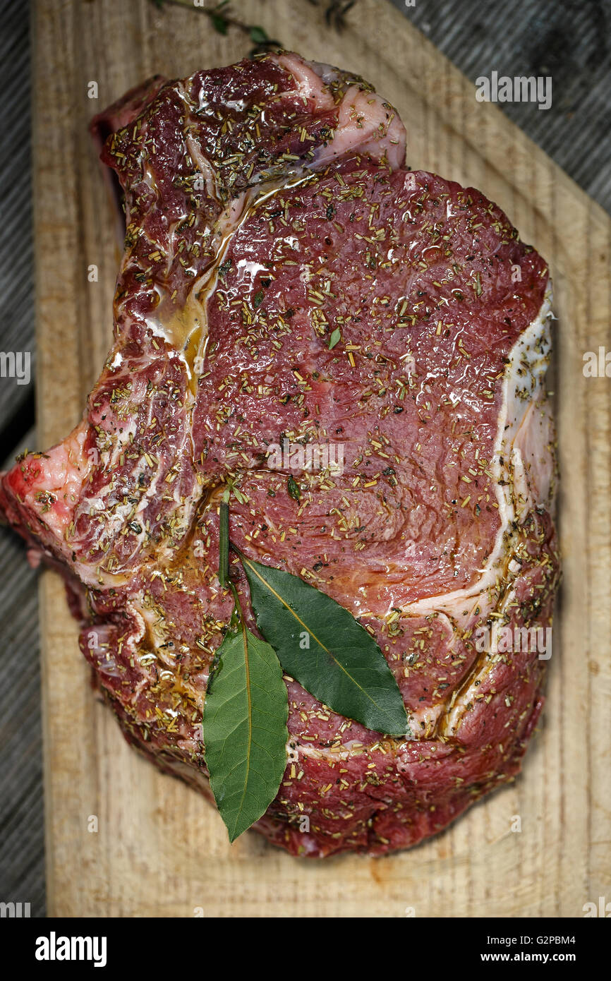 Large Fresh raw beef cutlet with spices on wooden board, ready for the grill Stock Photo
