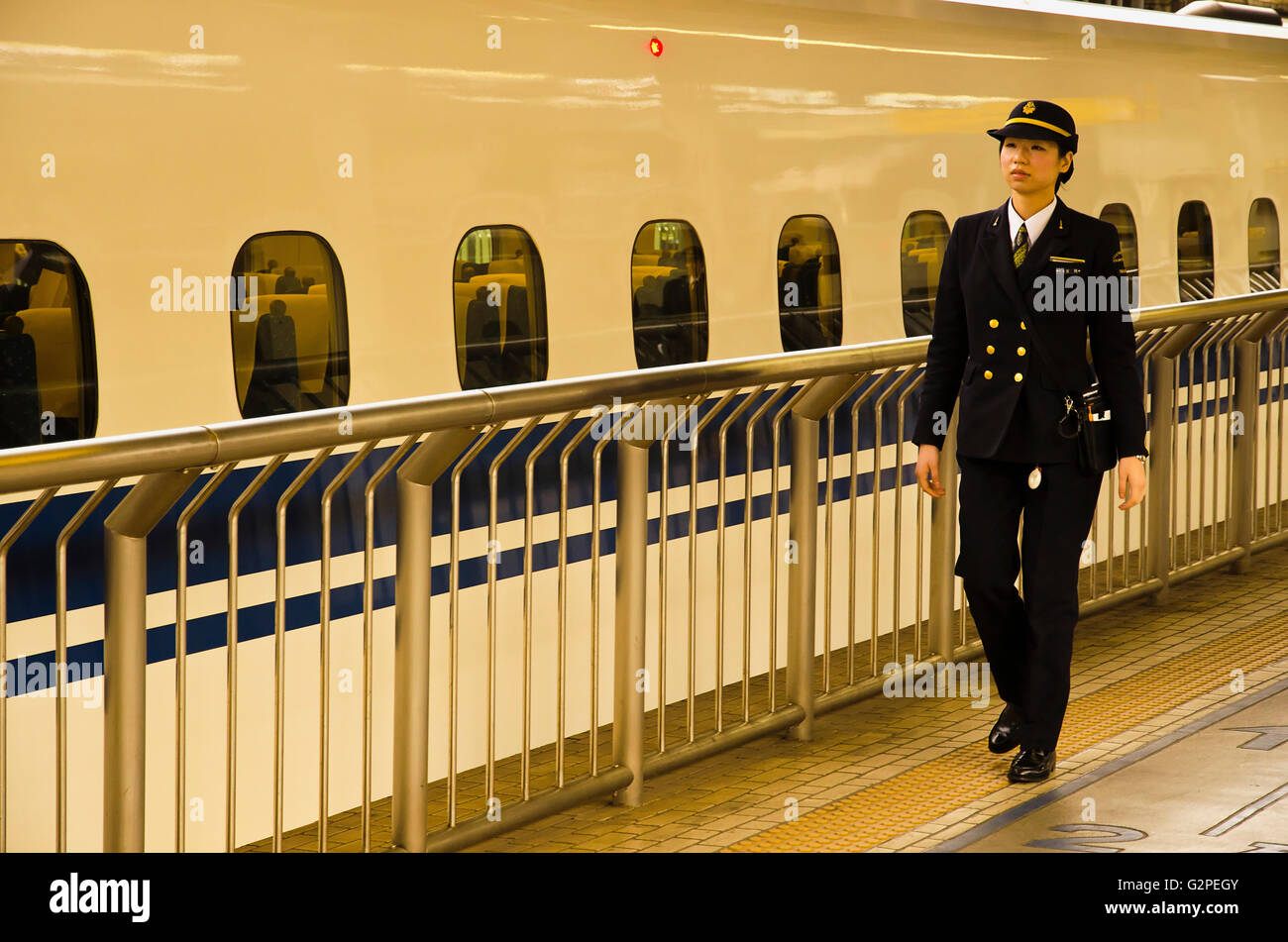 Japan, Tokyo, JR Tokyo station, on the train platform, a woman train driver about thirty years old, in JR uniform, walking to board shinkansen train. Stock Photo
