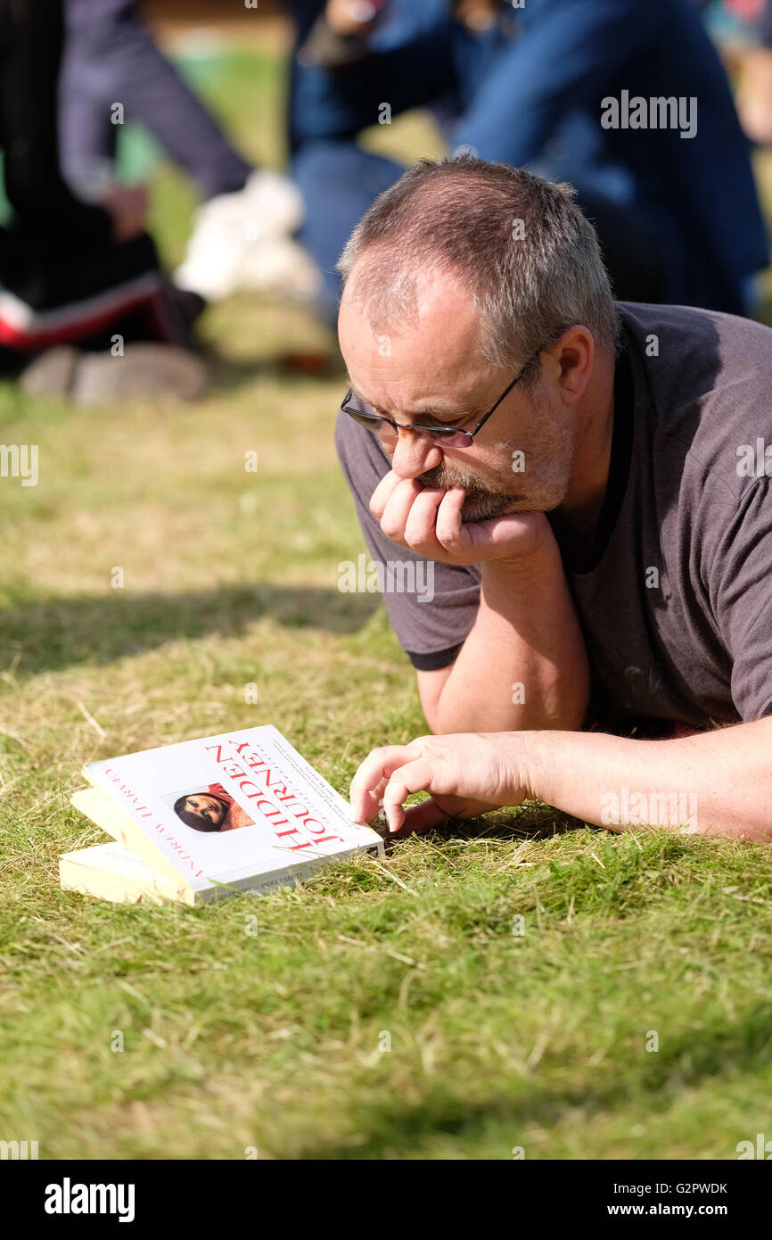 Hay Festival, Wales, UK - Thursday 2nd June 2016 -  A visitor looks at the cover of his new book on the lawns at the Hay Festival in the afternoon sunshine. Stock Photo