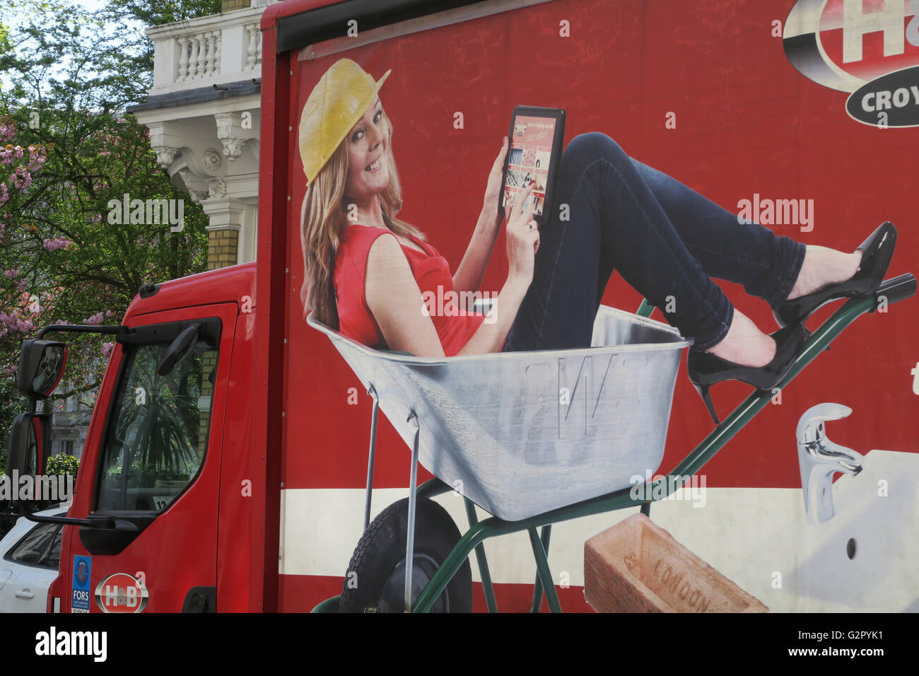 Woman/model sat in a wheelbarrow as part of an advert for a builder's merchants on a truck. Stock Photo