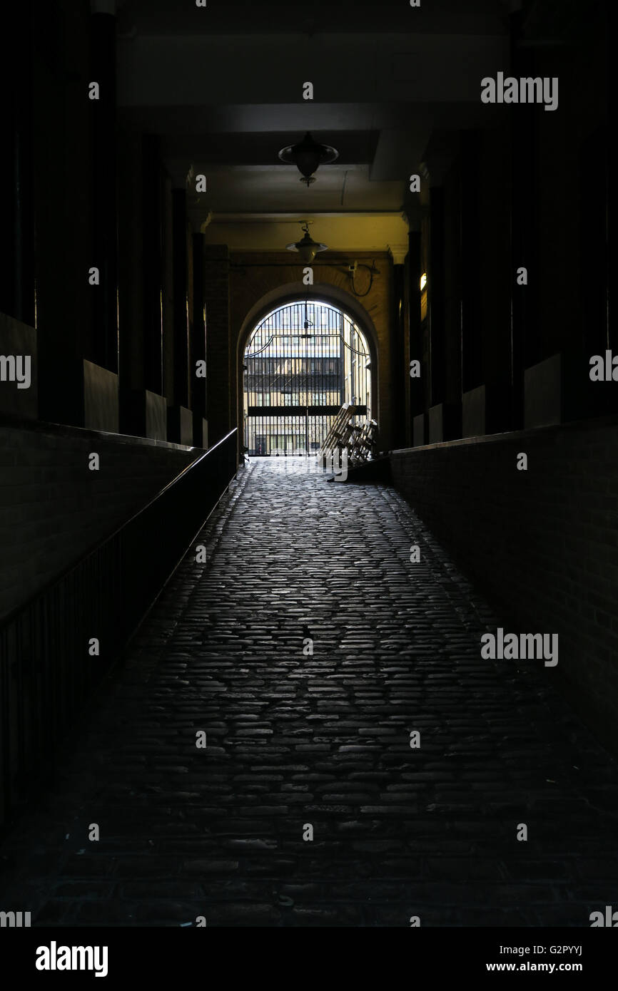 dark cobble stone alleyway / loading ramp with archway / gate Stock Photo