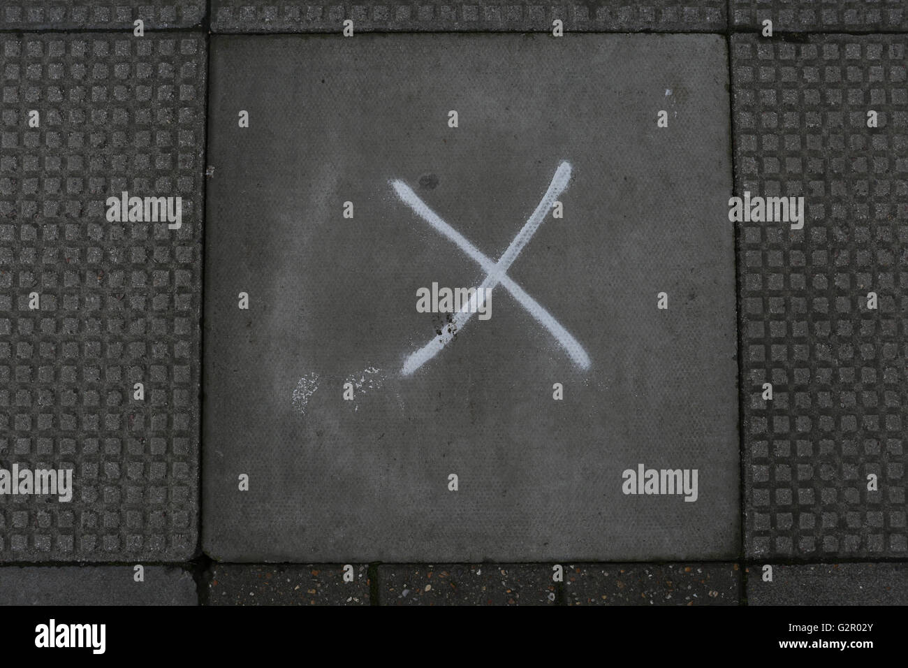 patterned paving slabs, with spray paint cross, x, road work markings