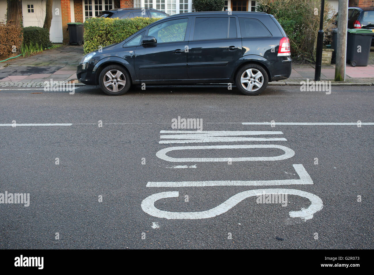 Slow road markings against a Vauxhall Zafira minivan, houses Stock Photo
