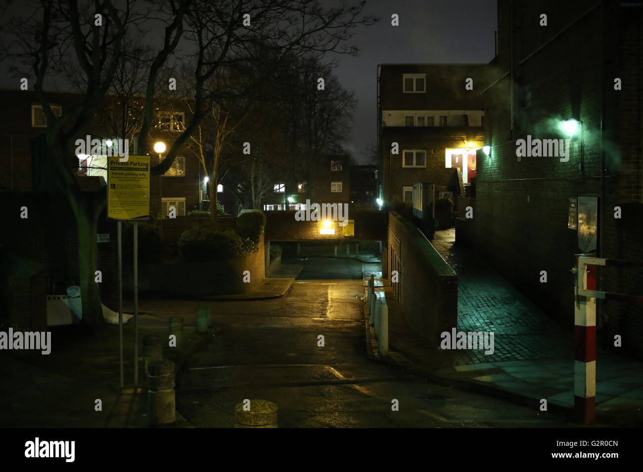 dimly lit road, car park entrance, alley, houses on a council housing estate in Archway, London Stock Photo