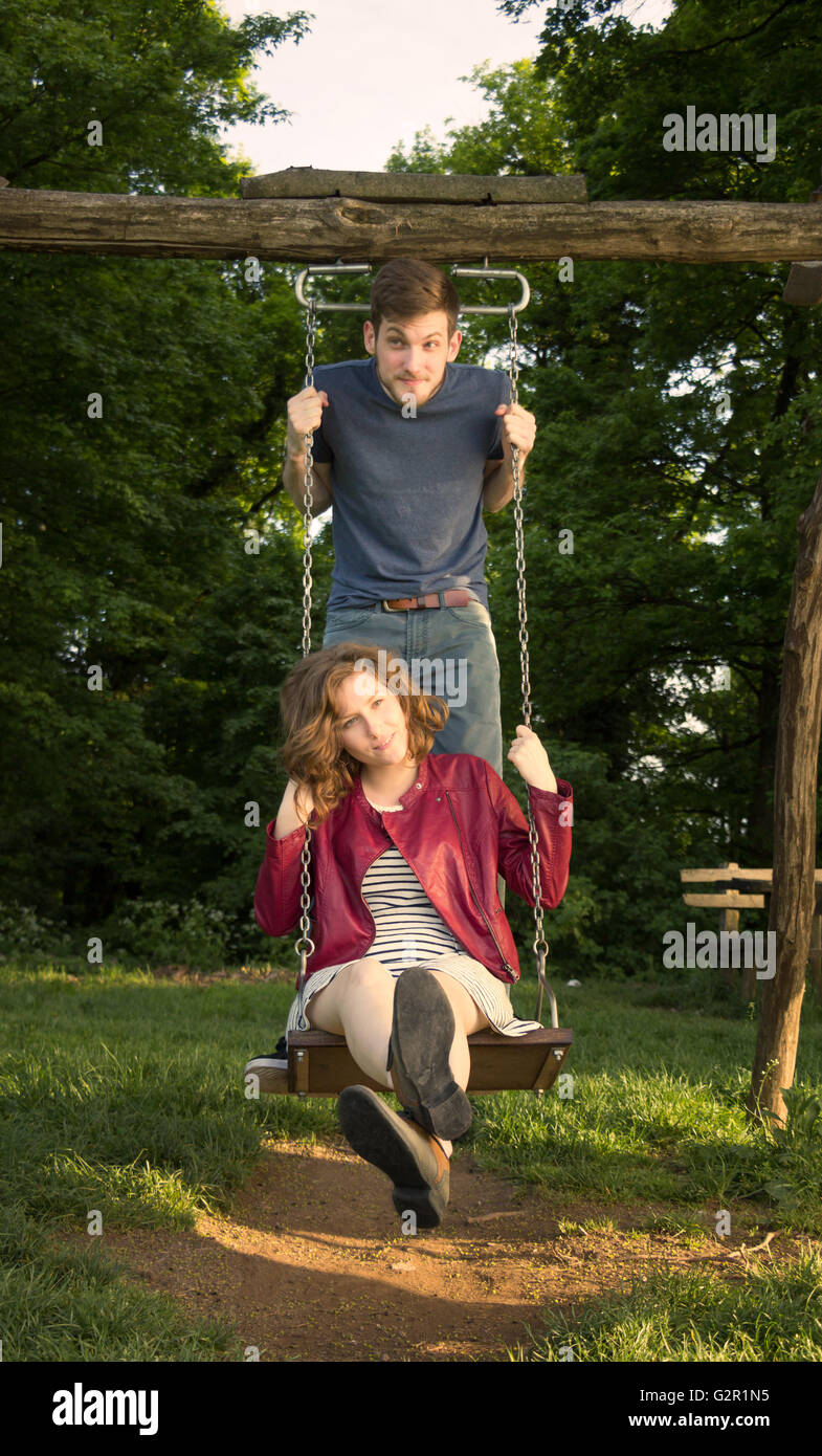 Cute girl and boy, on a swing, funny face expressions. Stock Photo