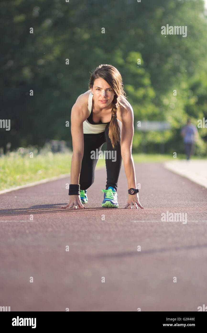 Girl kneeling run track, outdoors Stock Photo - Alamy