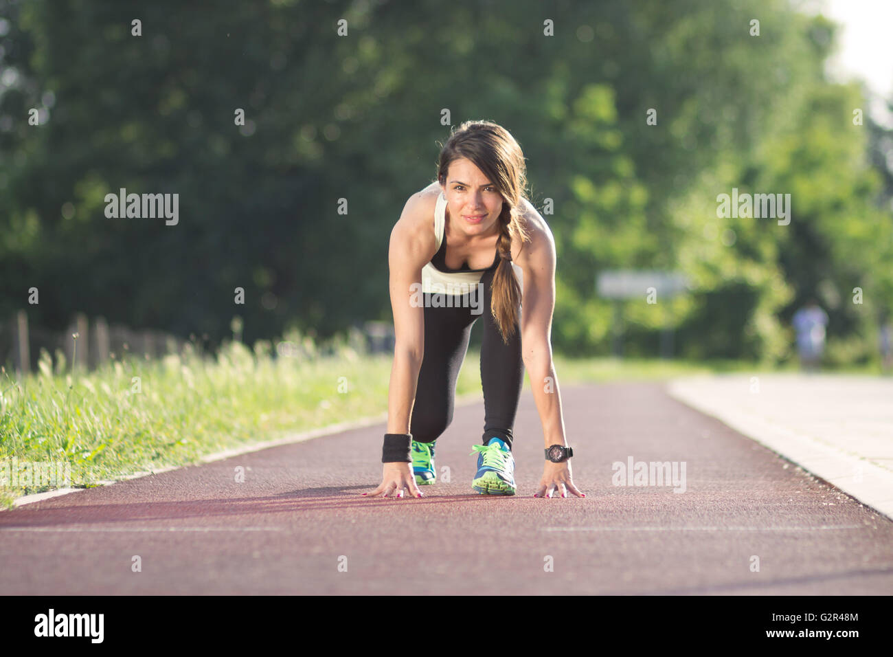 Smiling girl kneeling run track Stock Photo - Alamy