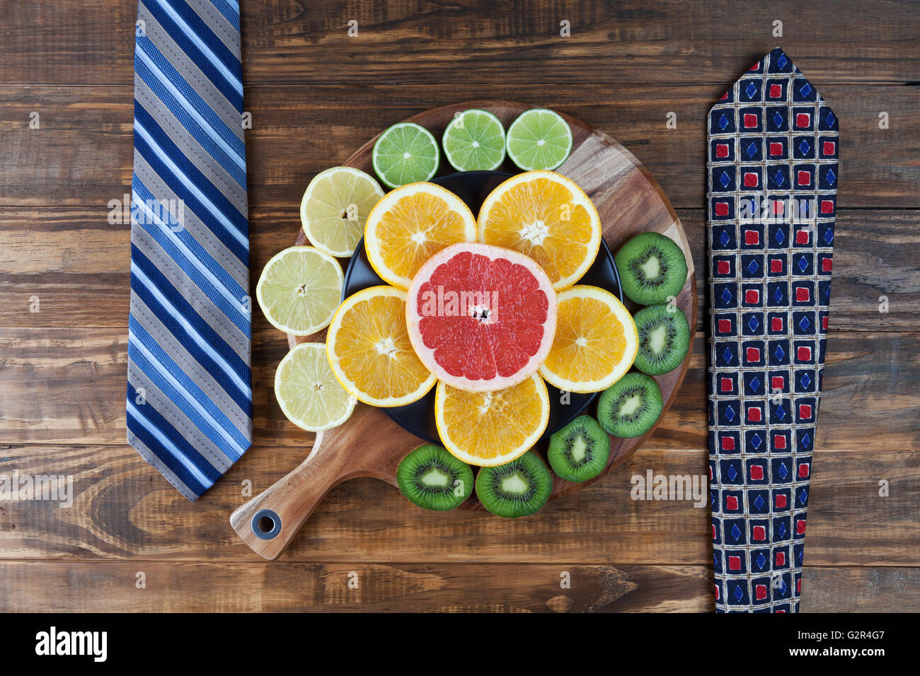 Healthy business lunch concept with ties and sliced citrus fruits on chopping board Stock Photo