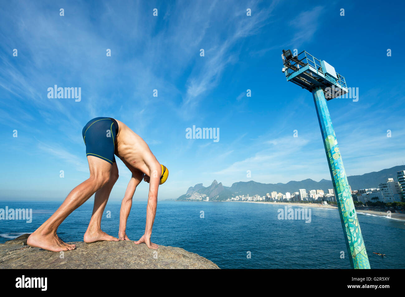 Pool Crounching Athlete swimmer with yellow swimming cap crouching in the start ...