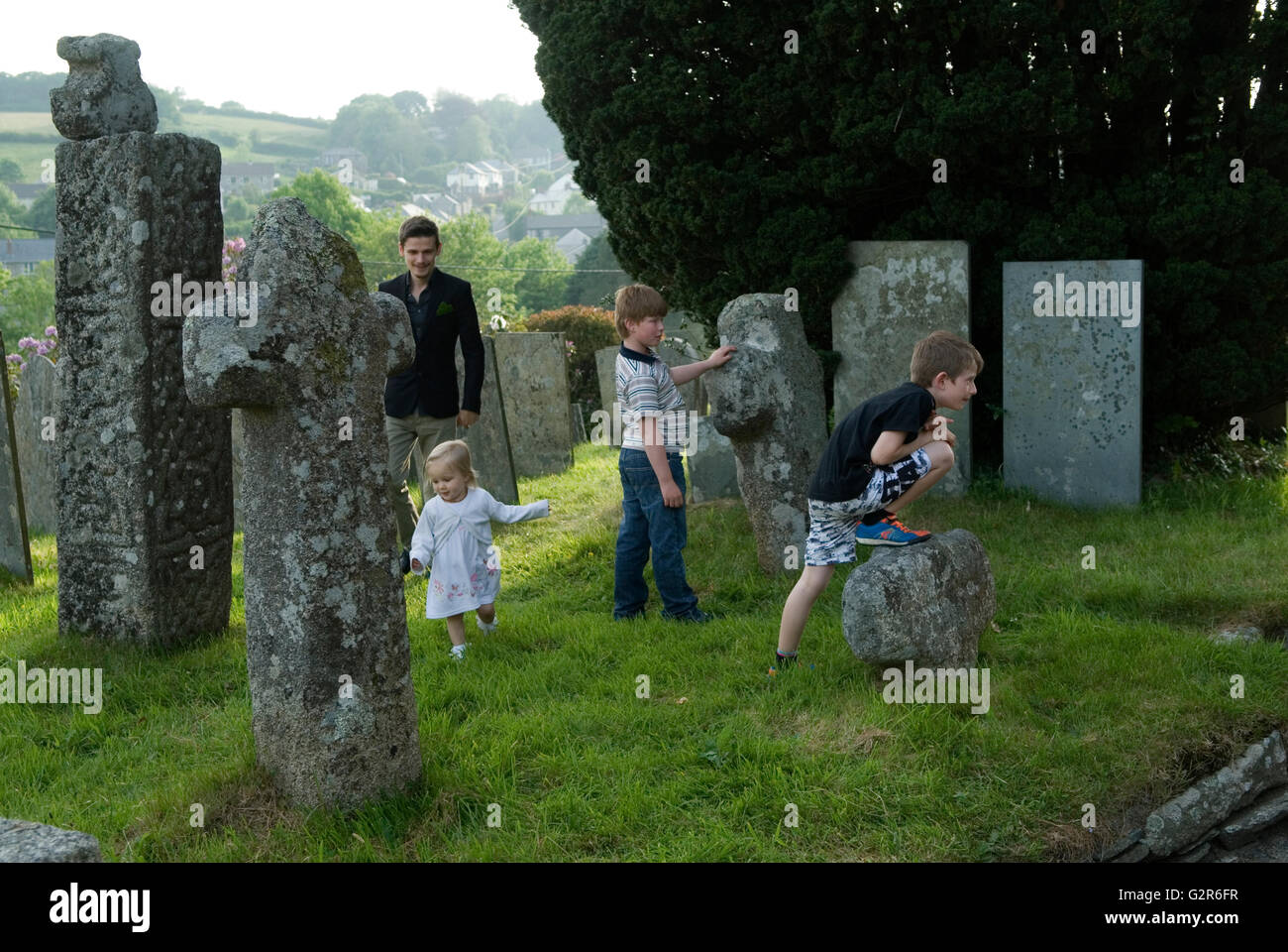 Children playing UK outside St Neot Cornwall. Ancient Celtic Crosses in the church yard. 2016 2010s HOMER SYKES Stock Photo