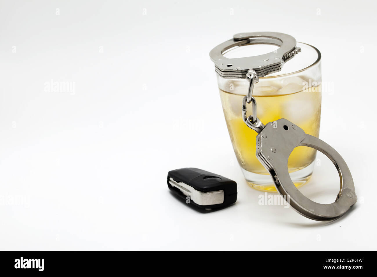 Car key with glass of whiskey and handcuffs - drive under influence concept. Stock Photo