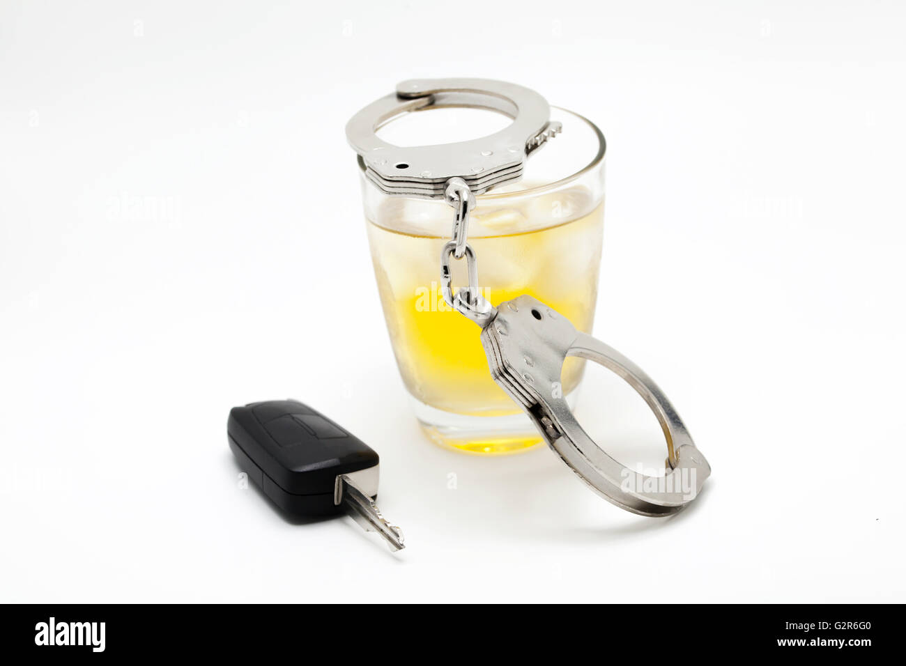 Car key with glass of whiskey and handcuffs - drive under influence concept. Stock Photo