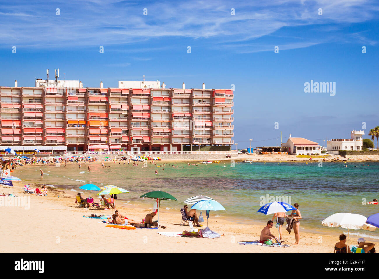 TORREVIEJA, SPAIN - SEPTEMBER 13, 2014: Sunny Mediterranean beach, Tourists relax on sand on loungers under parasols. Torrevieja Stock Photo
