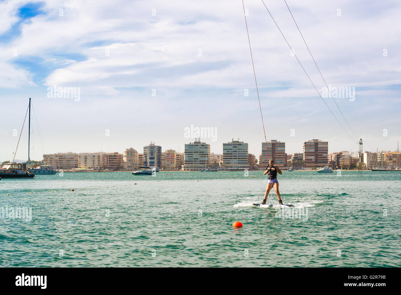 TORREVIEJA, SPAIN - SEPTEMBER 13, 2014: Cute girl learns to surf on background of yachts and boats in La Bocana, Cable Ski Stock Photo