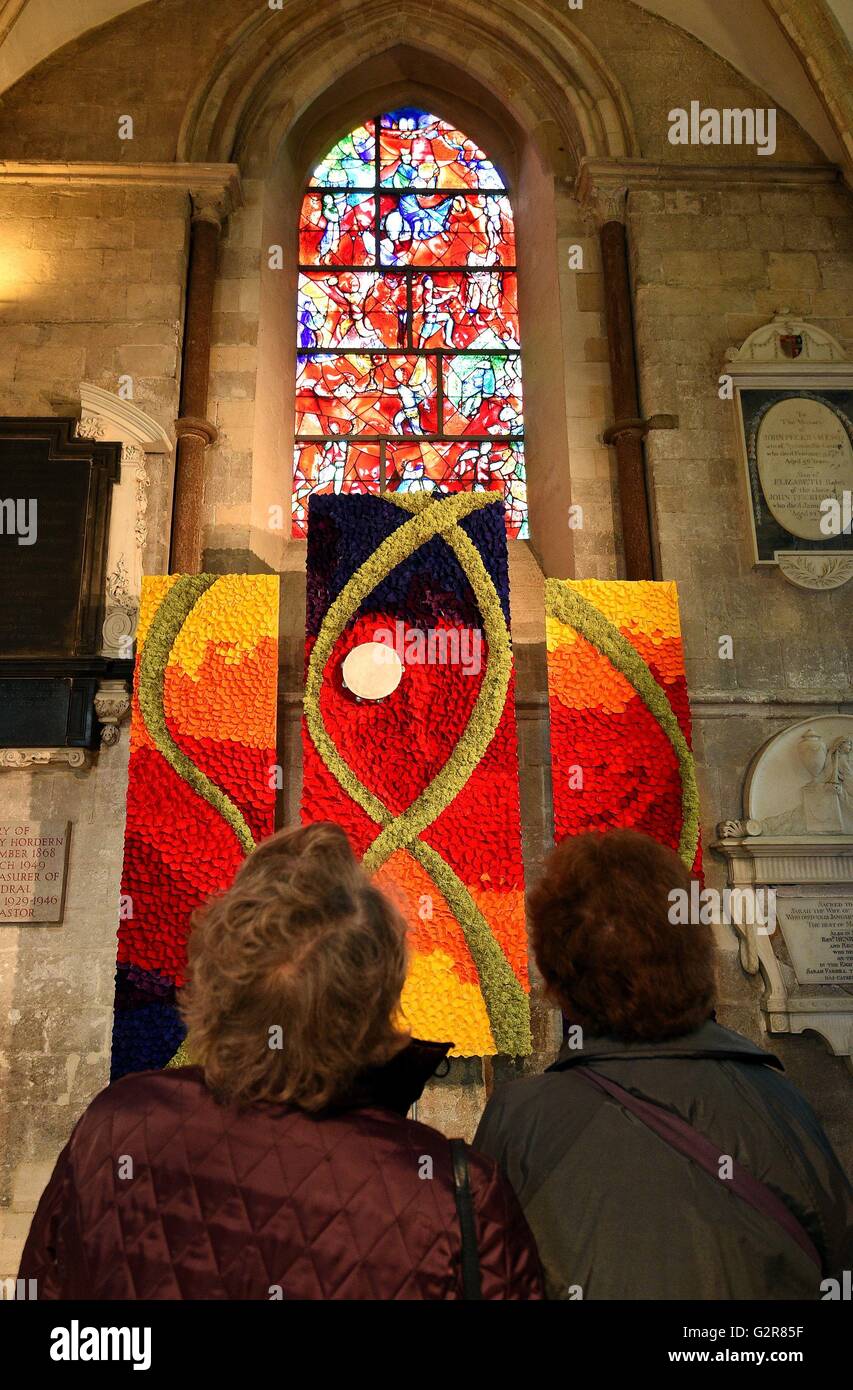 Members of the public view a piece called 'Praise Him with Tamborines and Dancing', underneath a stained glassed window by Marc Chagall inside Chichester Cathedral, which has been filled with 50,000 flowers to celebrate it's annual Festival of Flowers, which this year has the theme 'The Artists Palette'. Stock Photo