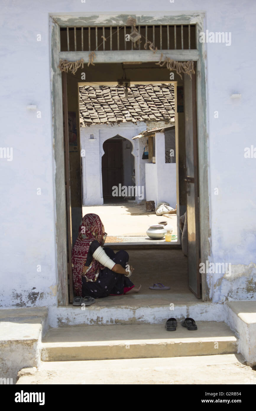 Lady sitting at door of house, Bera, Rajasthan, India Stock Photo