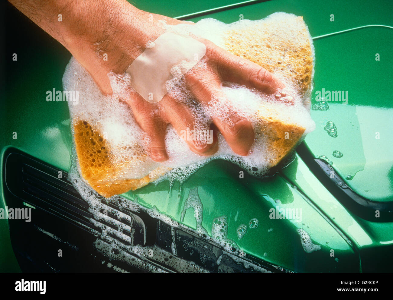 A mans hand washing a bright green car. Stock Photo