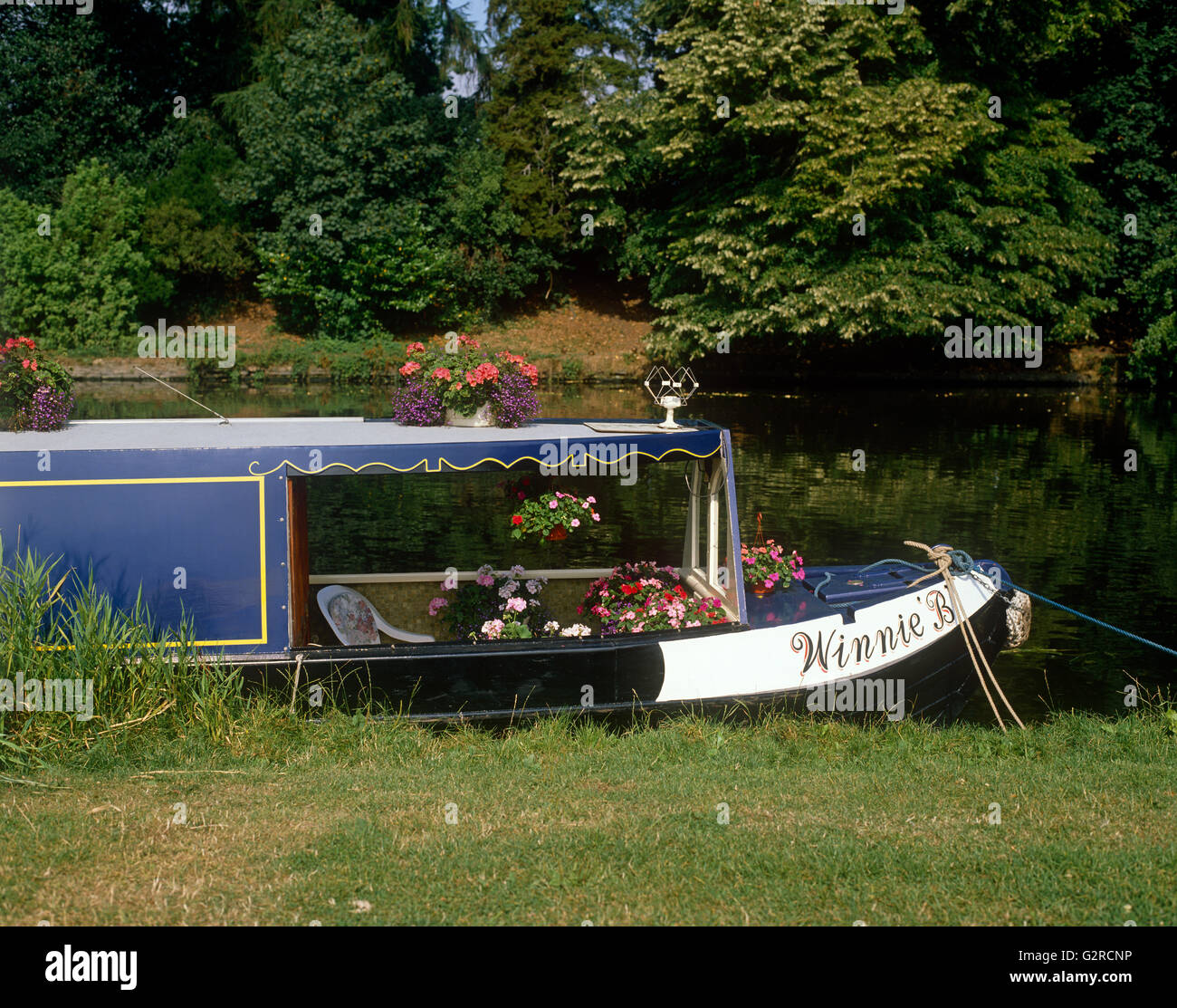 A canal boat, docked to the side of the river Stock Photo