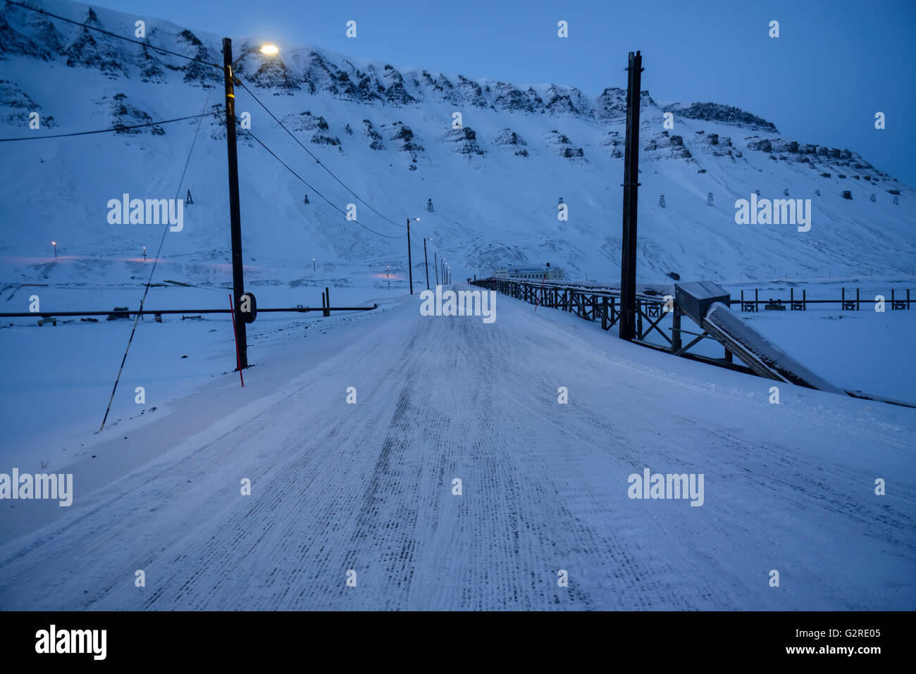 Snowcovered road in wintertime and polarnight in Longyear valley, Longyearbyen, Spitsbergen, Svalbard, Norway Stock Photo