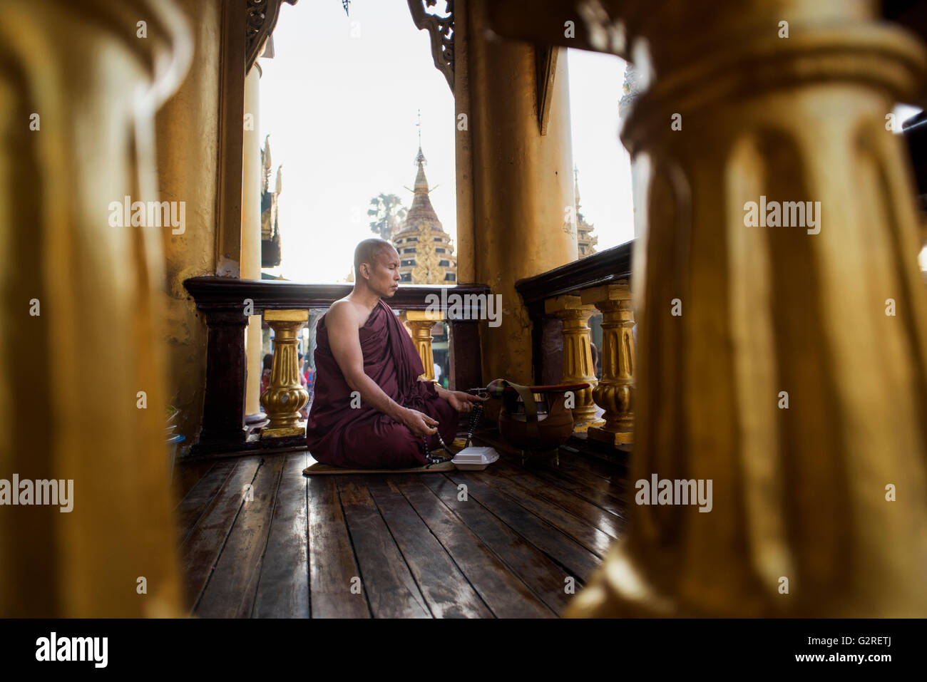 A Buddhist monk meditating at the Shwedagon pagoda, Yangon, Myanmar. Stock Photo