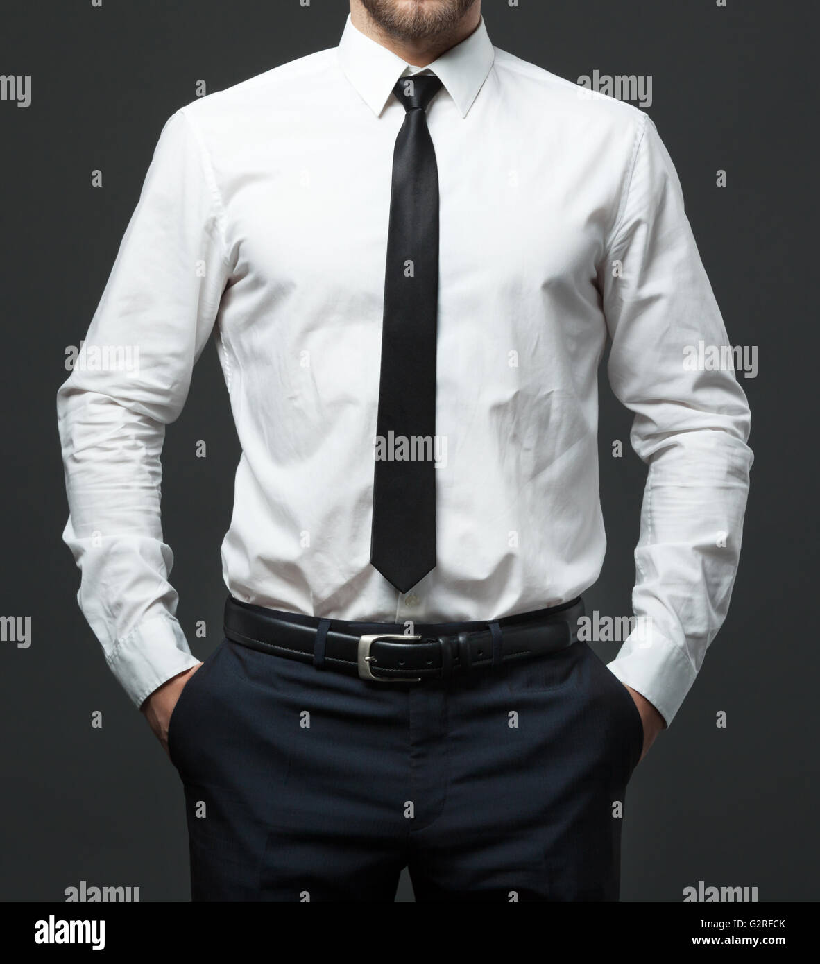 Midsection of fit young businessman standing in formal white shirt, black tie and pants. Stock Photo