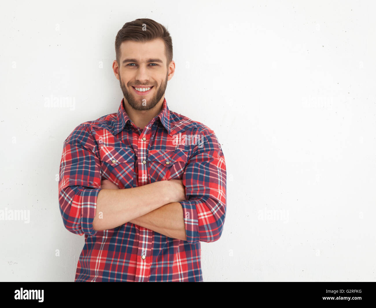Portrait of handsome young guy standing against white wall Stock Photo ...